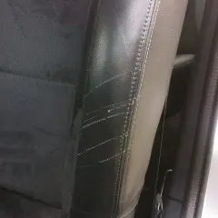Siège de voiture en cuir noir avec des rayures visibles sur le côté, un problème courant pour ceux qui cherchent comment enlever les rayures sur chaussures vernis.