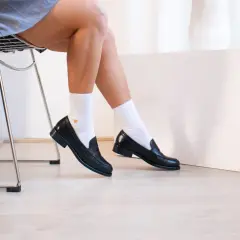 Une tenue chic avec mocassin femme noir, chaussettes blanches et une jupe grise. Parfait pour un look décontracté et élégant.