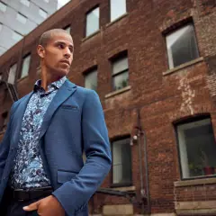 Un homme porte un costume bleu avec une chemise à motifs floraux, prêt à porter des bas au bureau.