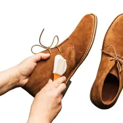 Nettoyage d'une chaussure en cuir retourné avec une brosse.