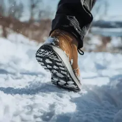 Une chaussure pour marcher dans la neige, avec une semelle crantée pour une bonne adhérence. Le pied avance dans la poudreuse.