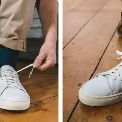 Un homme ajuste sa tenue avec une chaussure blanche homme, des chaussettes à vélos et un pantalon beige retroussé.
