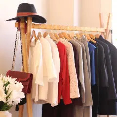 Un portant à vêtements avec un chapeau, des sacs et des vêtements. Une idée pour savoir comment arrêter d'acheter des vêtements.