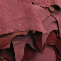 Superposition de pièces de croute de cuir bordeaux, matière brute prête à être transformée.