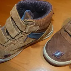 Paire de bottines marron avec des patchs noirs et roses sur le bout de chaussure abîmé.