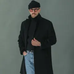 Un homme porte un manteau noir, un pull à col roulé, un bonnet et des lunettes. Faut-il prendre une taille au-dessus pour un manteau ?