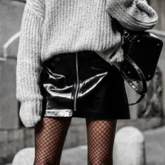 Une idée tenue avec collant résille : jupe vinyle noire, pull gris oversize et sac structuré.