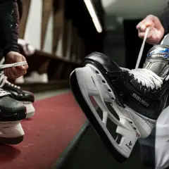 Des patineurs se préparent à entrer sur la glace, ils commencent à **poser soi même patin chaussure** pour le match.