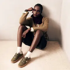 Une femme pose, assise au sol, portant des baskets vertes femme stylées avec des détails léopard.