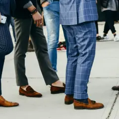 Un groupe d'hommes élégants, leurs pantalons tombant sur leurs chaussures, arborent des styles variés, du costume à rayures aux jeans.