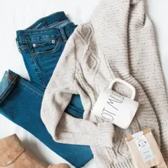 Ensemble pour s'habiller en hiver : jean, pull torsadé, bottines beiges, tasse et sachet de thé.
