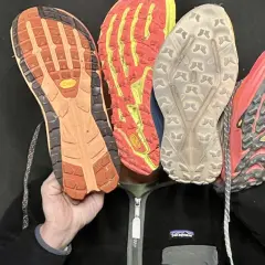 Qu'est-ce qu'une semelle Vibram ? Quatre semelles de chaussures de trail, dont une Vibram orange, montrent leur adhérence.