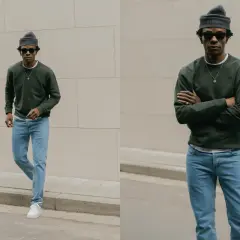 Un homme porte une tenue jean bleu décontractée, un pull vert foncé et un bonnet gris.