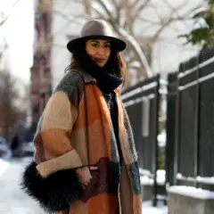 Une femme élégante avec un manteau coloré, un chapeau et un sac en fourrure, parfaite pour savoir comment s'habiller en hiver femme.