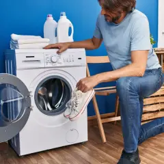 Un homme prépare ses baskets pour le lavage. Il se demande à combien laver des chaussures pour qu'elles ressortent comme neuves.