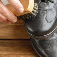 Maintenir le cuir en bon état : une brosse nettoie une chaussure noire pour réparer le cuir craquelé.