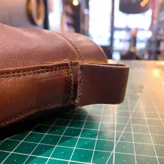 Gros plan sur une chaussure en cuir marron, montrant une déchirure à réparer. Le travail de réparation du cuir déchiré d'une chaussure est en cours.
