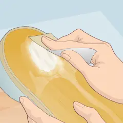Main d'une personne appliquant une pâte blanche sur la semelle d'une chaussure, peut-être pour réparer une semelle qui se désagrège.