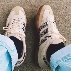 Un homme porte des sneakers Adidas beige avec des détails ethniques, un outfit décontracté parfait pour la belle saison.
