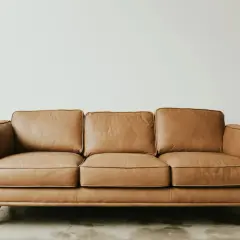 Canapé trois places en cuir aniline, couleur caramel, sur pieds en bois. Un fauteuil confortable pour votre salon.