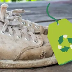 Vieilles baskets usées avec un symbole de recyclage vert. Une question se pose : où jeter des chaussures ?