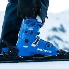 Une chaussure de ski Salomon bleue vif, prête pour la piste. Les boucles noires et blanches sont ajustées, la neige est au rendez-vous.