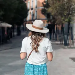 Une femme porte un chapeau et une robe fleurie, idéale pour savoir quelle couleur porter quand il fait chaud.