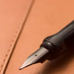Plume d'un stylo plume noir sur un cuir brun. Une question se pose : comment enlever du stylo sur du cuir ?