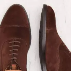 Deux chaussures richelieu en daim marron. La semelle est en cuir ou gomme, offrant confort et durabilité.