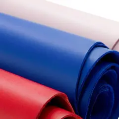 Rouleaux de cuir coloré, rouge, bleu et rose pâle, évoquant la douceur d'une vachette animal.