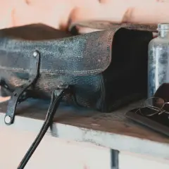 Sacoche en cuir moisi, lunettes anciennes et flacons poussiéreux sur une étagère. Le bicarbonate de soude pourrait aider à rafraîchir ce cuir.