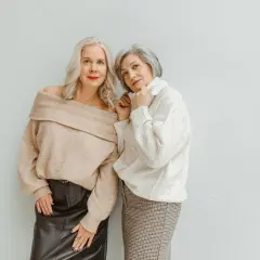 Deux femmes élégantes, l'une en pull beige dénudant ses épaules et jupe en cuir, l'autre en pull blanc et jupe à carreaux, prouvent qu'il n'y a pas d'erreurs de style qui vieillissent.