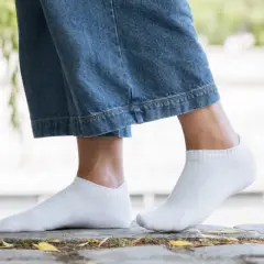 Pieds féminins en chaussettes blanches discrètes, idéales avec des baskets blanches pour un look casual.