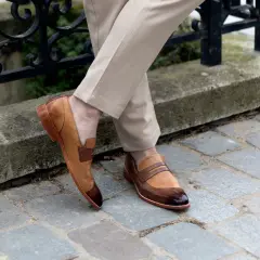 Un homme porte des mocassins bicolores en cuir, un style parfait pour une promenade en ville. Pas de marron dans la ville, juste du style !
