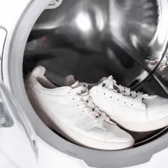 Paire de baskets blanches dans le tambour d'une machine à laver.