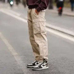 Un homme porte un pantalon cargo beige et une chaussure de sport iconique, prêt pour une journée en ville.