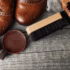 Paire de chaussures en cuir marron, cirage, applicateur et brosses pour vernir chaussures.