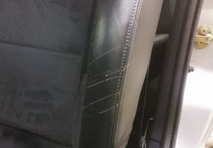 Siège de voiture en cuir noir avec des rayures visibles sur le côté, un problème courant pour ceux qui cherchent comment enlever les rayures sur chaussures vernis.