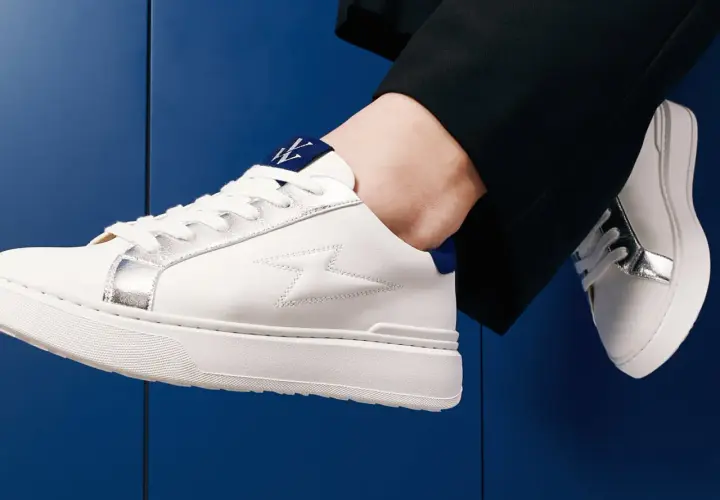 Baskets blanches homme avec détails argentés et logo bleu. Parfaites avec un pantalon noir, elles répondent à la question : quelles chaussettes avec baskets blanches homme ?