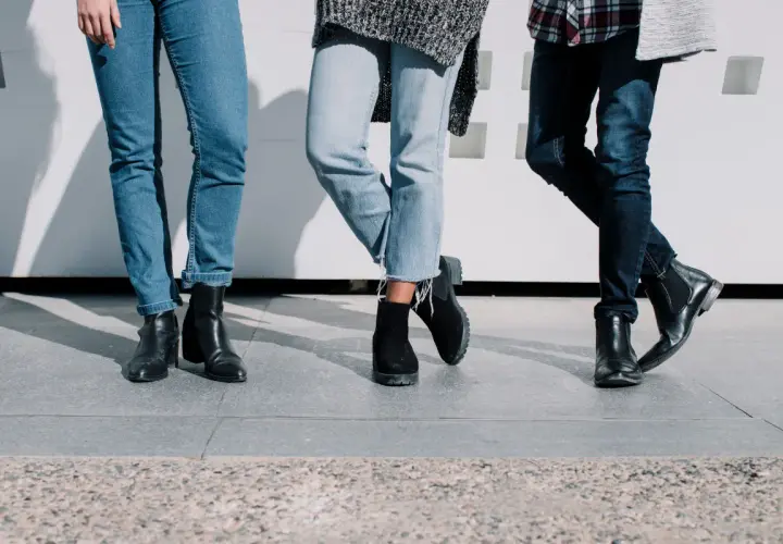 Trois paires de jambes portant des jeans et des bottes, un look décontracté et stylé.