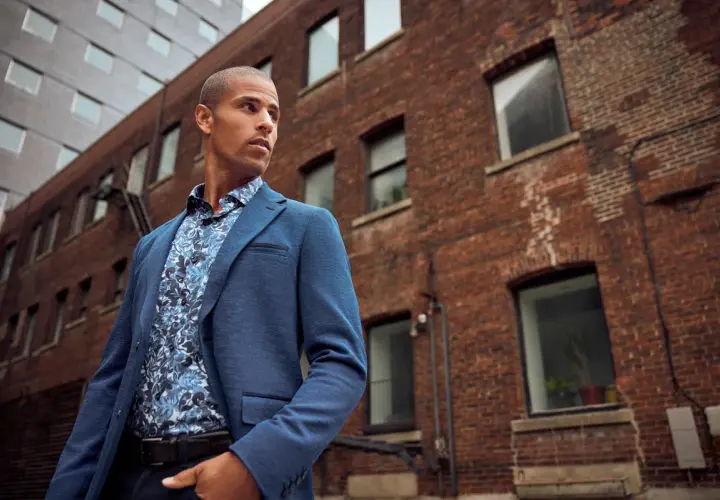 Un homme porte un costume bleu avec une chemise à motifs floraux, prêt à porter des bas au bureau.