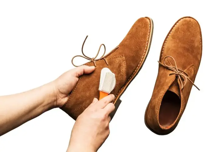 Nettoyage d'une chaussure en cuir retourné avec une brosse.
