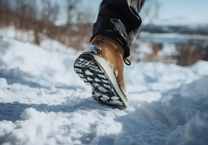 Une chaussure pour marcher dans la neige, avec une semelle crantée pour une bonne adhérence. Le pied avance dans la poudreuse.