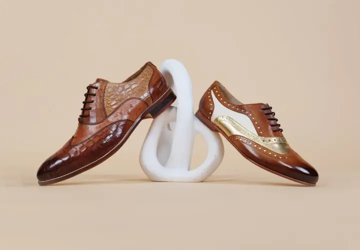 Comment porter des richelieu femme : deux paires de chaussures élégantes en cuir marron, ornées de textures et de détails dorés, posées sur un socle blanc.