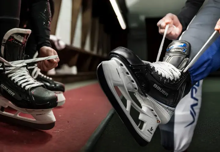 Des patineurs se préparent à entrer sur la glace, ils commencent à **poser soi même patin chaussure** pour le match.
