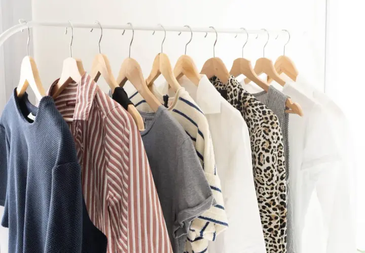 Vêtements sur un portant : une garde-robe minimaliste pour comment éviter la surconsommation. Bleu, rayé, léopard, blanc... des pièces intemporelles.