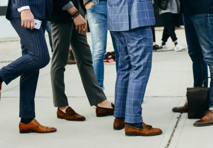 Un groupe d'hommes élégants, leurs pantalons tombant sur leurs chaussures, arborent des styles variés, du costume à rayures aux jeans.