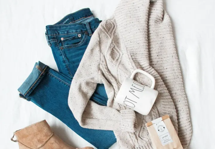 Ensemble pour s'habiller en hiver : jean, pull torsadé, bottines beiges, tasse et sachet de thé.