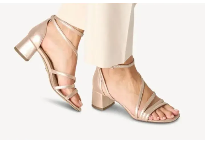 Sandales à talons carrés dorées, avec brides fines croisées sur le pied. Quel vernis avec chaussures dorées ? Un nude ou un rose pâle serait parfait.