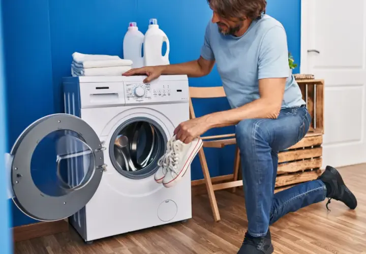 Un homme prépare ses baskets pour le lavage. Il se demande à combien laver des chaussures pour qu'elles ressortent comme neuves.